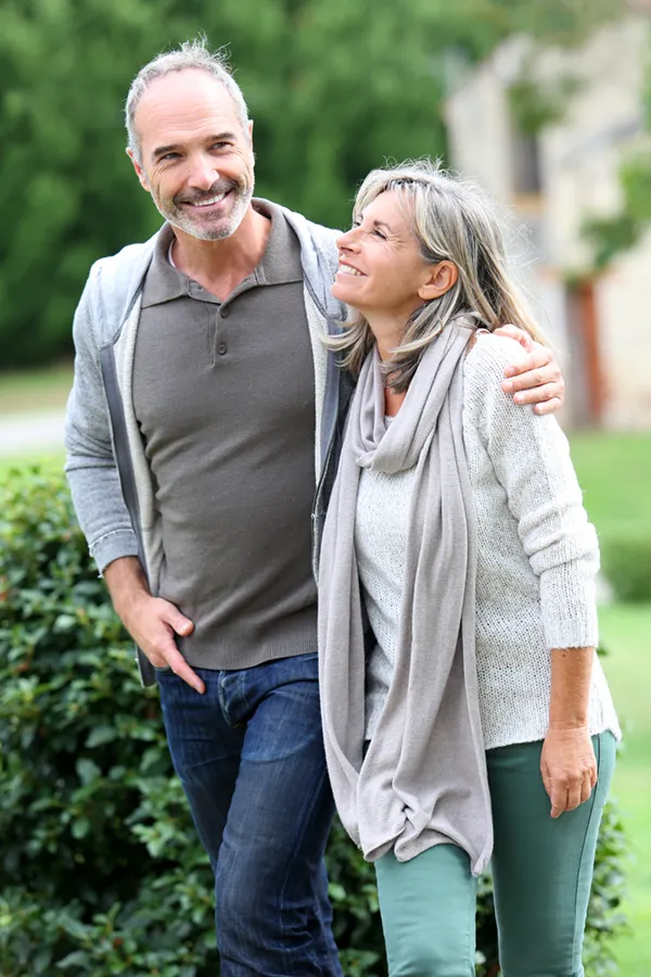 Bioidentical-Hormone-Therapy-Treatment A mature couple in gray toned clothes and jeans walk happily outside, happy with their successful bioidentical hormone treatments from Tanya Zboril, NP of TBT Medical in Kitchener-Waterloo.