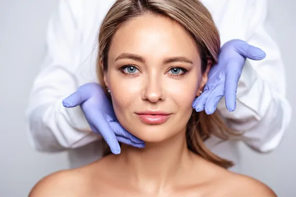 Botox-Doctor Close up of a woman's face with a doctor wearing rubber gloves standing behind her holding his hands around her face to show the amazing Botox Cosmetic treatment from Tanya Zboril, NP of TBT Medical in Kitchener-Waterloo.