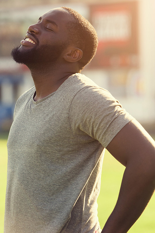 Lean-Muscle-and-Recovery-Treatment A black man in a gray t-shirt and smiles, looking up with closed eyes after a satisfying workout. Get treatment for lean muscle loss and recovery from Tanya Zboril, NP of TBT Medical in Kitchener-Waterloo.