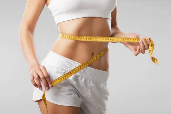 Low-Dose-Naltrexone-for-Weight-Loss-Doctor A woman wraps a measuring tape around her waist to show the success of her Low Dose Naltrexone for Weight Loss treatments from Tanya Zboril, NP of TBT Medical in Kitchener-Waterloo.