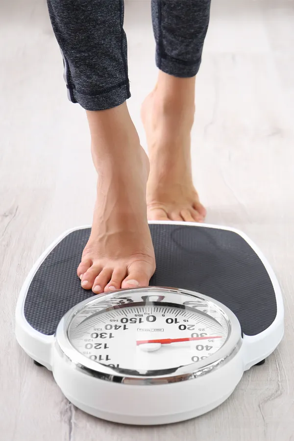 Obesity-Treatment Close up of feet stepping onto a scale. Receive expert functional medicine for obesity treatment by Tanya Zboril, NP of TBT Medical in Kitchener-Waterloo.