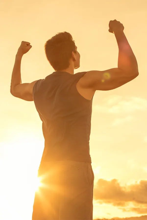 Wegovy-Weight-Loss-Treatment A motivational image of a young man standing with his back to the camera, arms raised triumphantly against a sunrise. Representing Wegovy Weight Loss Injections offered by Tanya Zboril, NP of TBT Medical in Kitchener-Waterloo.